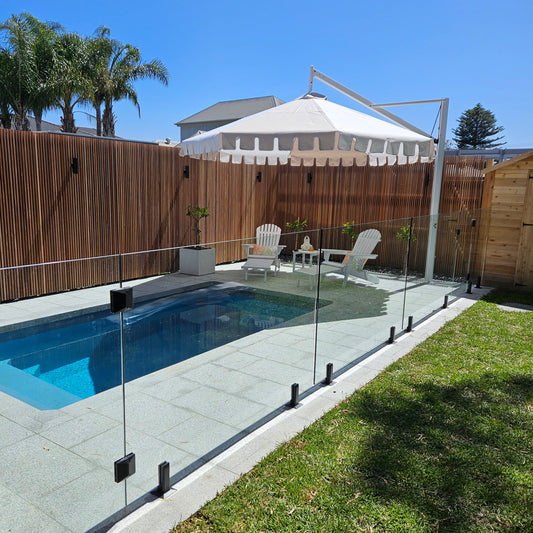 Backyard with pool, deck, and outdoor furniture under a clear blue sky.